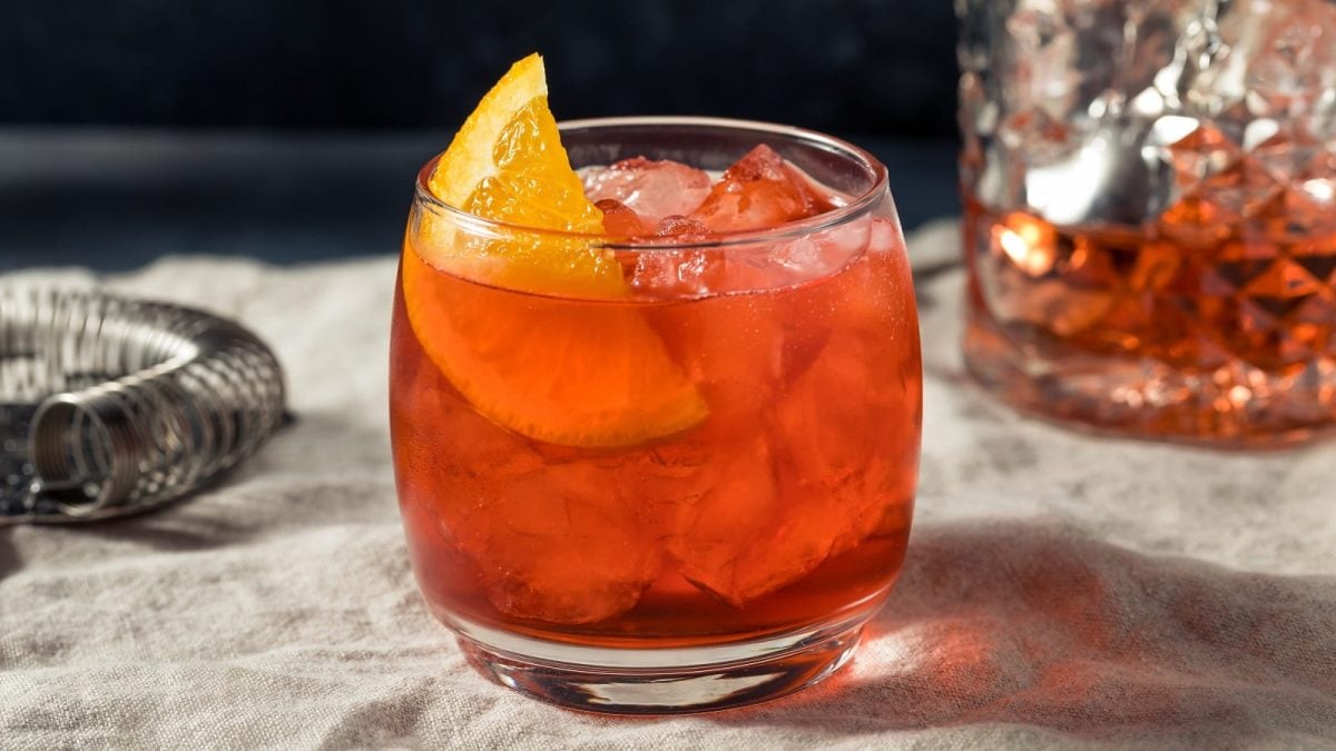 Ein Glas mit alkoholfreiem Negroni auf einem Tuch.