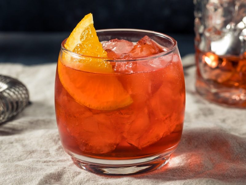 Ein Glas mit alkoholfreiem Negroni auf einem Tuch.