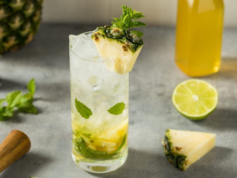 Ein Glas Ananas-Mojito auf einem grauen Tisch.