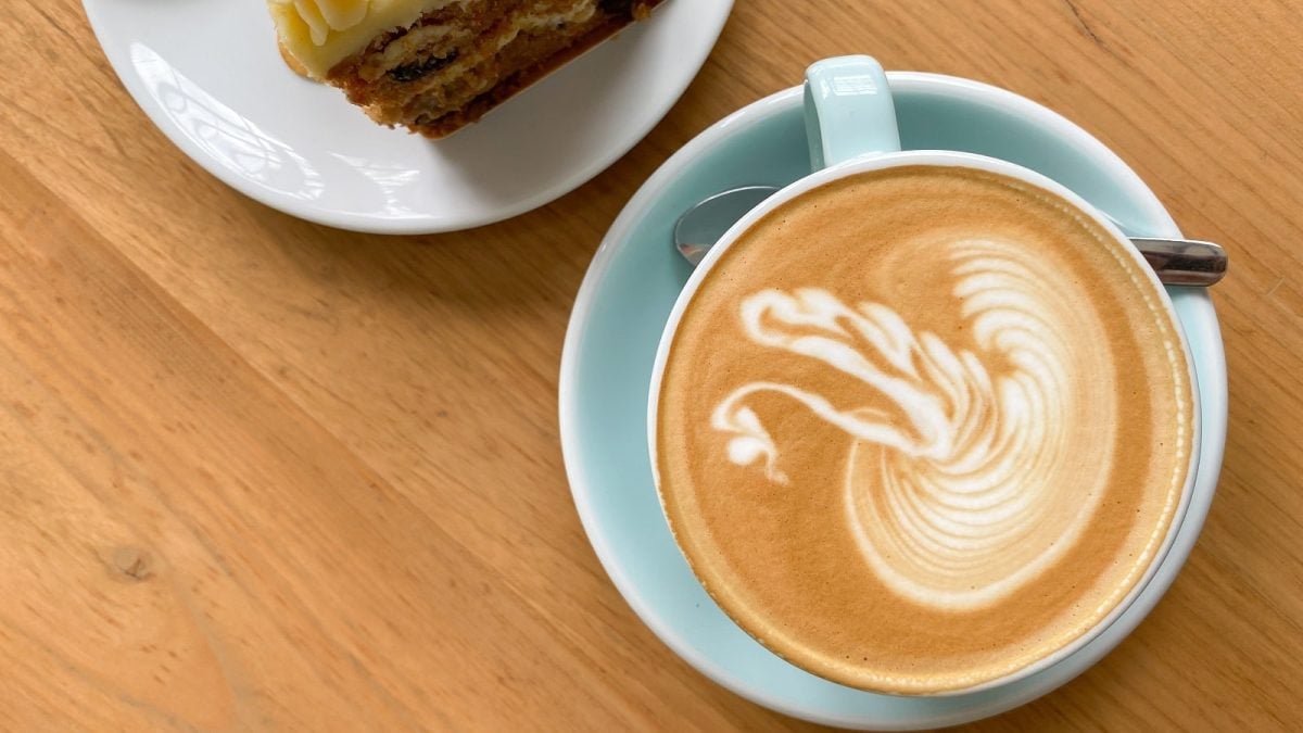 Eine hellblaue Tasse mit Carrot Cake Latte auf einem Holztisch.