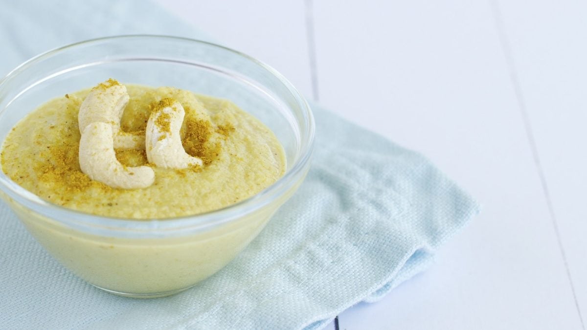 Eine Schüssel mit Cashew-Curry-Dip auf einem blauen Geschirrtuch.