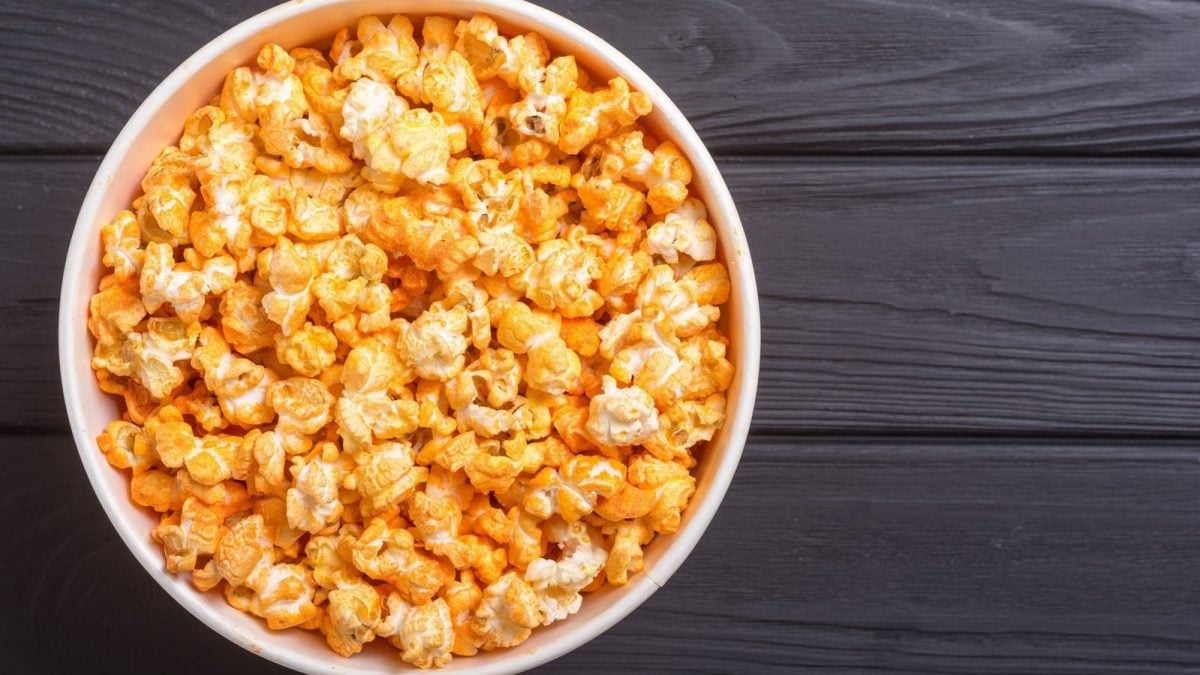 Eine Schüssel mit Chili Cheese Popcorn auf einem grauen Holztisch.