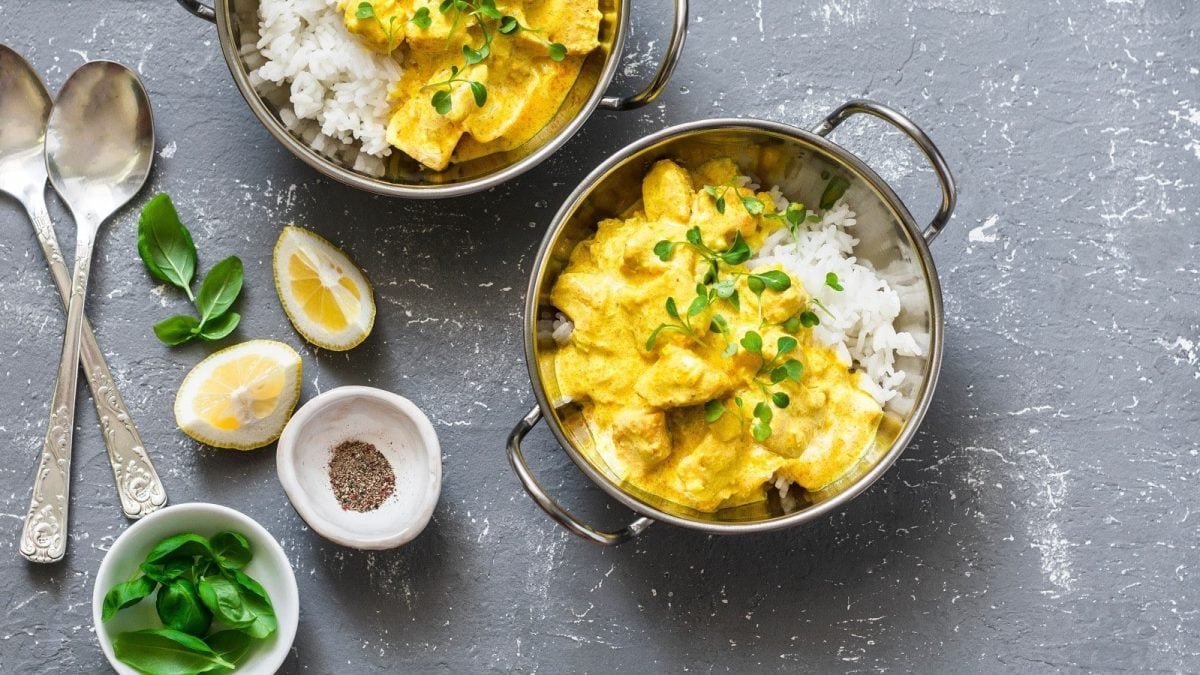 Eine Schüssel mit gelbem Lachs-Curry auf einem grauen Hintergrund.