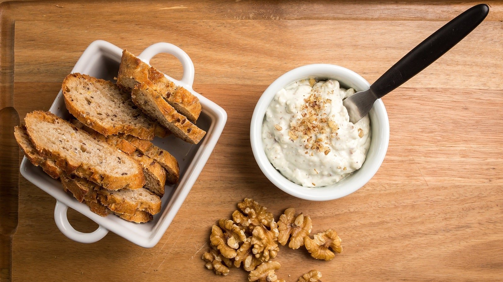 Eine kleine Schüssel mit Knoblauch-Walnuss-Dip auf einem Holzbrett.