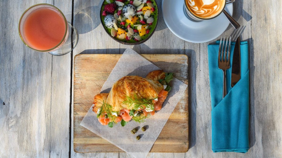 Ein Teller mit gefülltem Lachs-Croissant auf einem gedeckten Frühstückstisch.