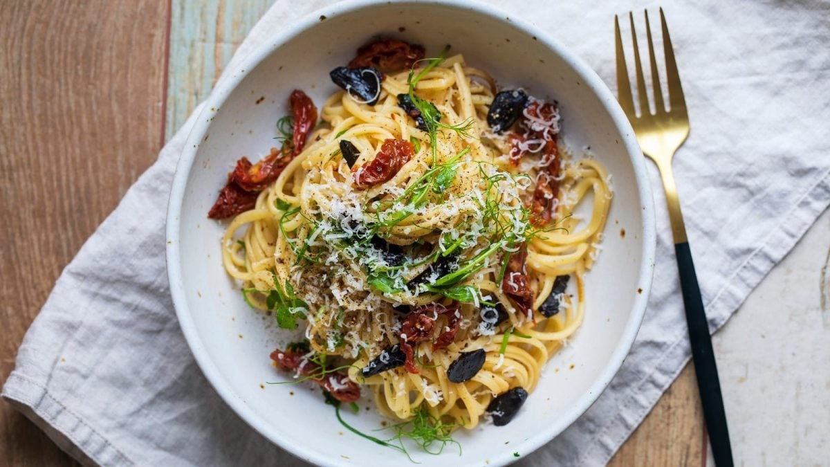 Ein runder Teller mit Pasta mit schwarzem Knoblauch.