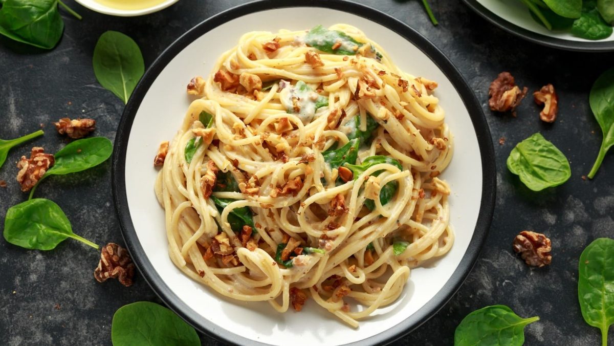 Ein Teller mit Pasta mit Walnussbutter auf einem dunkelgrauen Tisch.