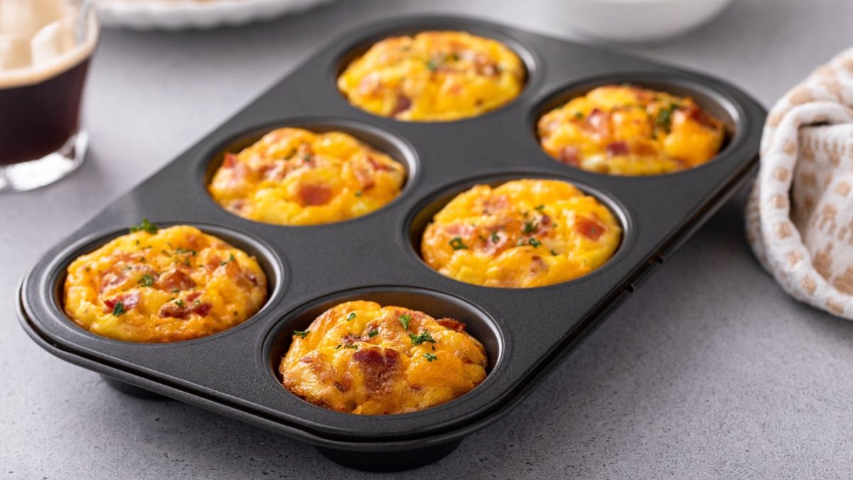 Eine muffinform mit den Eier-Muffins auf einem hellgrauen Tisch.