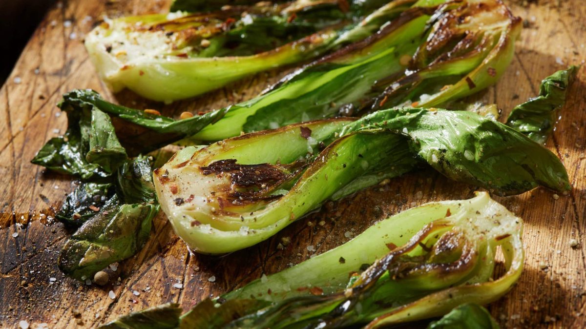Gerösteter Pak Choi Hot & Spicy auf Holzbrett angerichtet. Draufsicht.