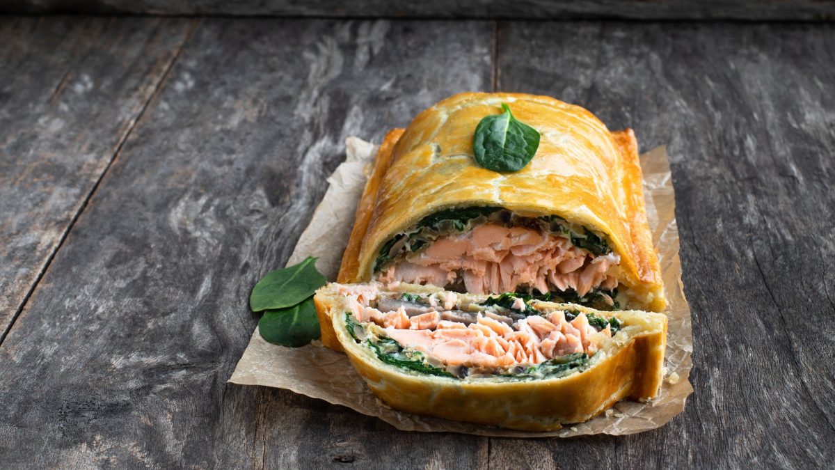 Lachs-Coulibiac Lachs Wellington auf Alufolie auf grauem Untergrund. Frontalansicht