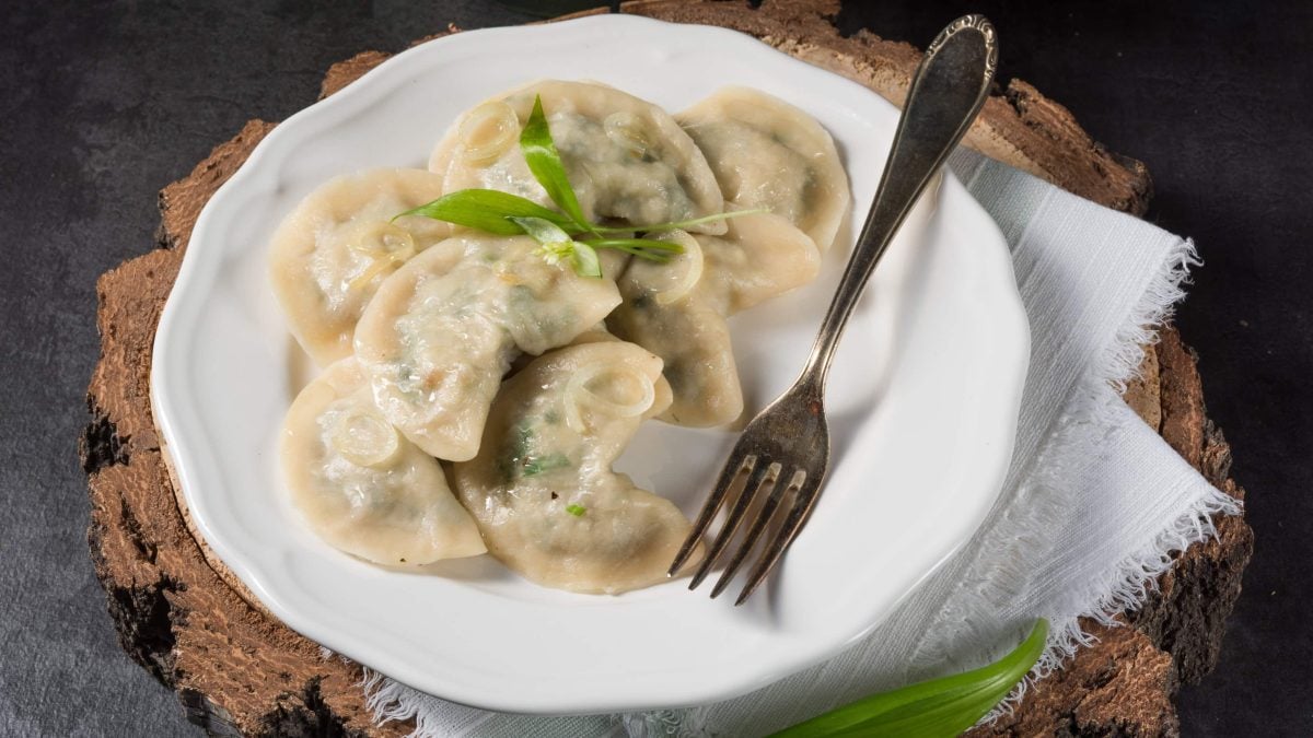 Draufsicht: Ein Teller Bärlauch-Maultaschen steht auf einem dunklen Untergrund aus Holz