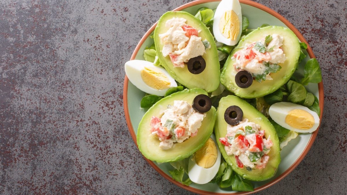 Palta Reine chilenische gefüllte Avocado mit Hähnchensalat auf Teller und grauem Untergrund. Draufsicht.
