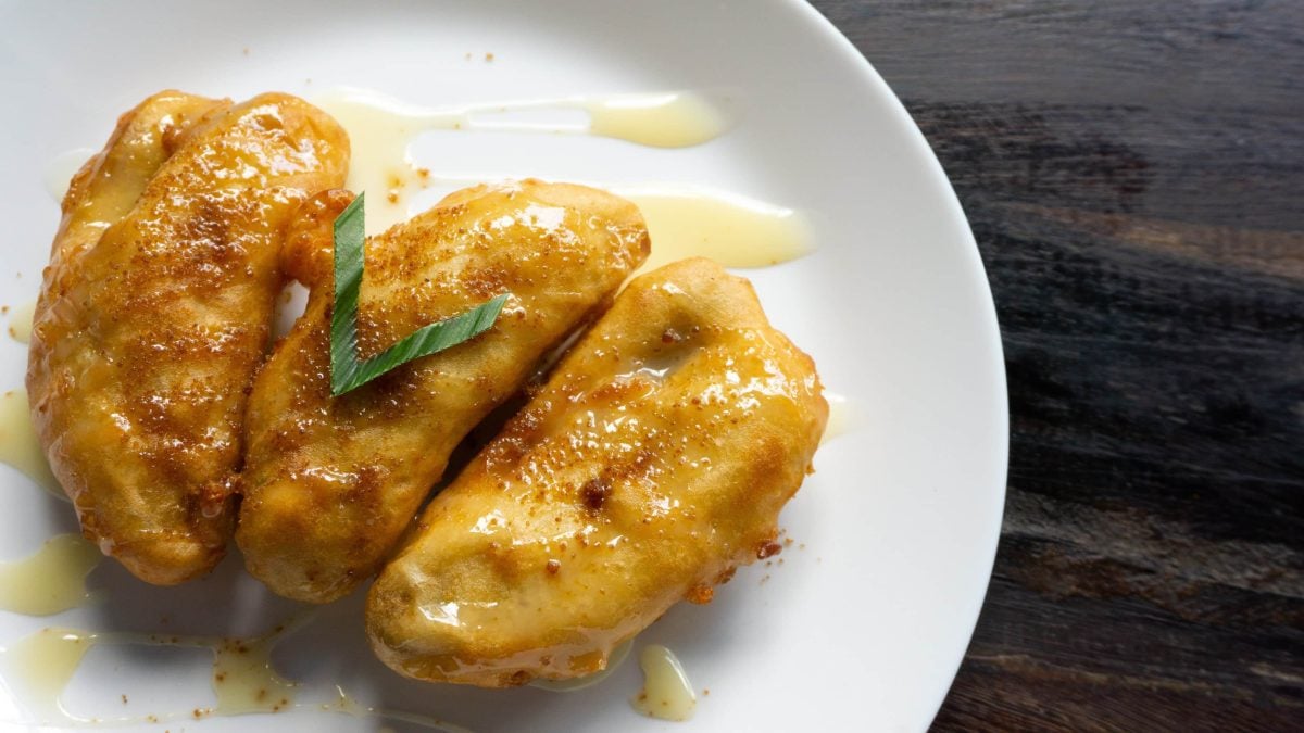 Pisang Goreng frittierte Bananen mit Honigsauce aus Indonesien auf weißem Teller. Draufsicht.