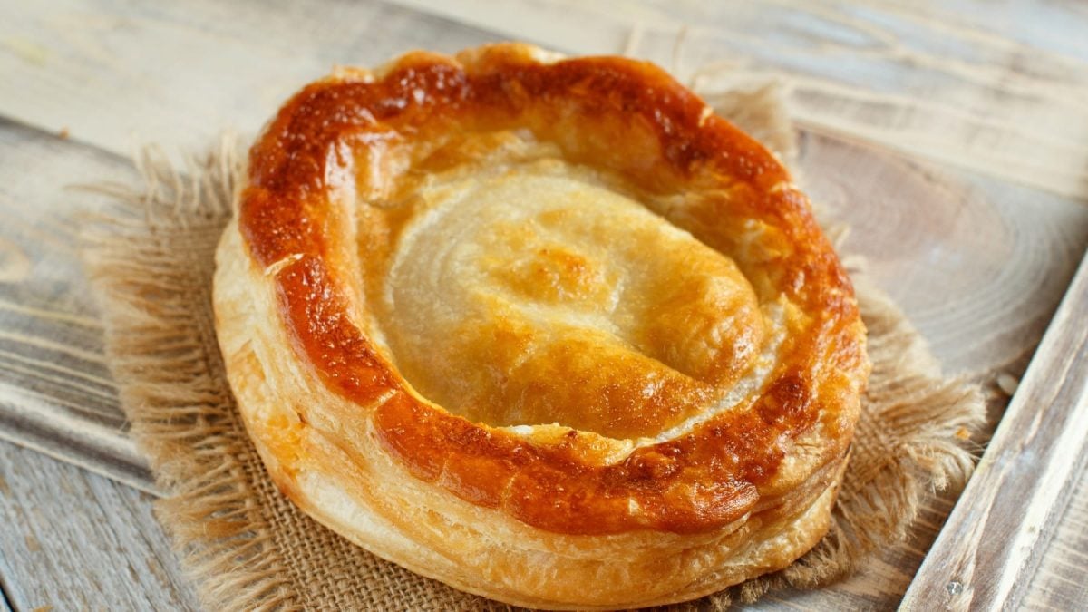 Ein Blätterteiggebäck auf einem hellen Holzbrett.