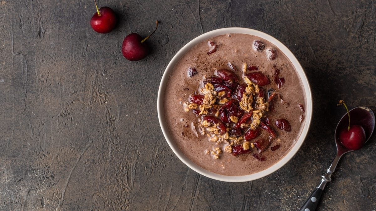 Eine runde Schüssel mit Schwarzwälder Kirschporridge auf einem grauen Steinuntergrund.