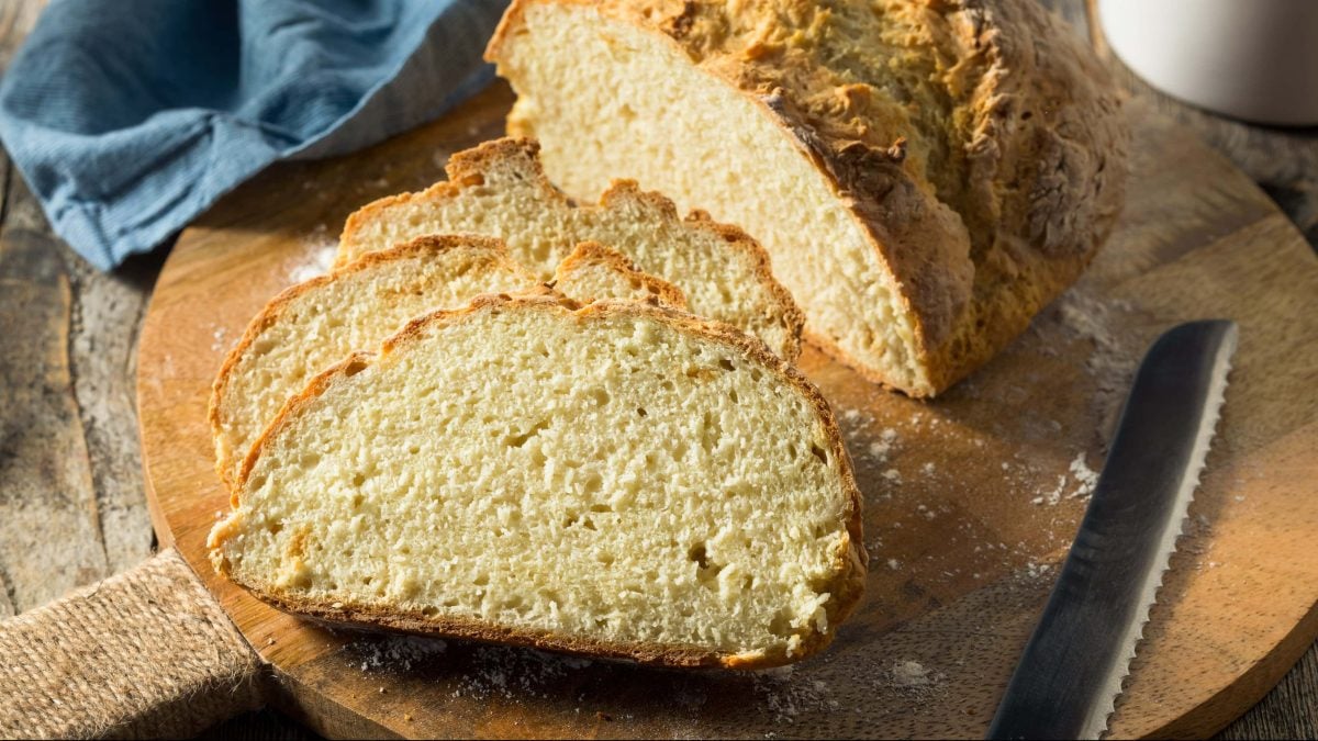 Frontalsicht: ein angeschnittenes Buttermilchbrot auf einem Holzbrettchen.