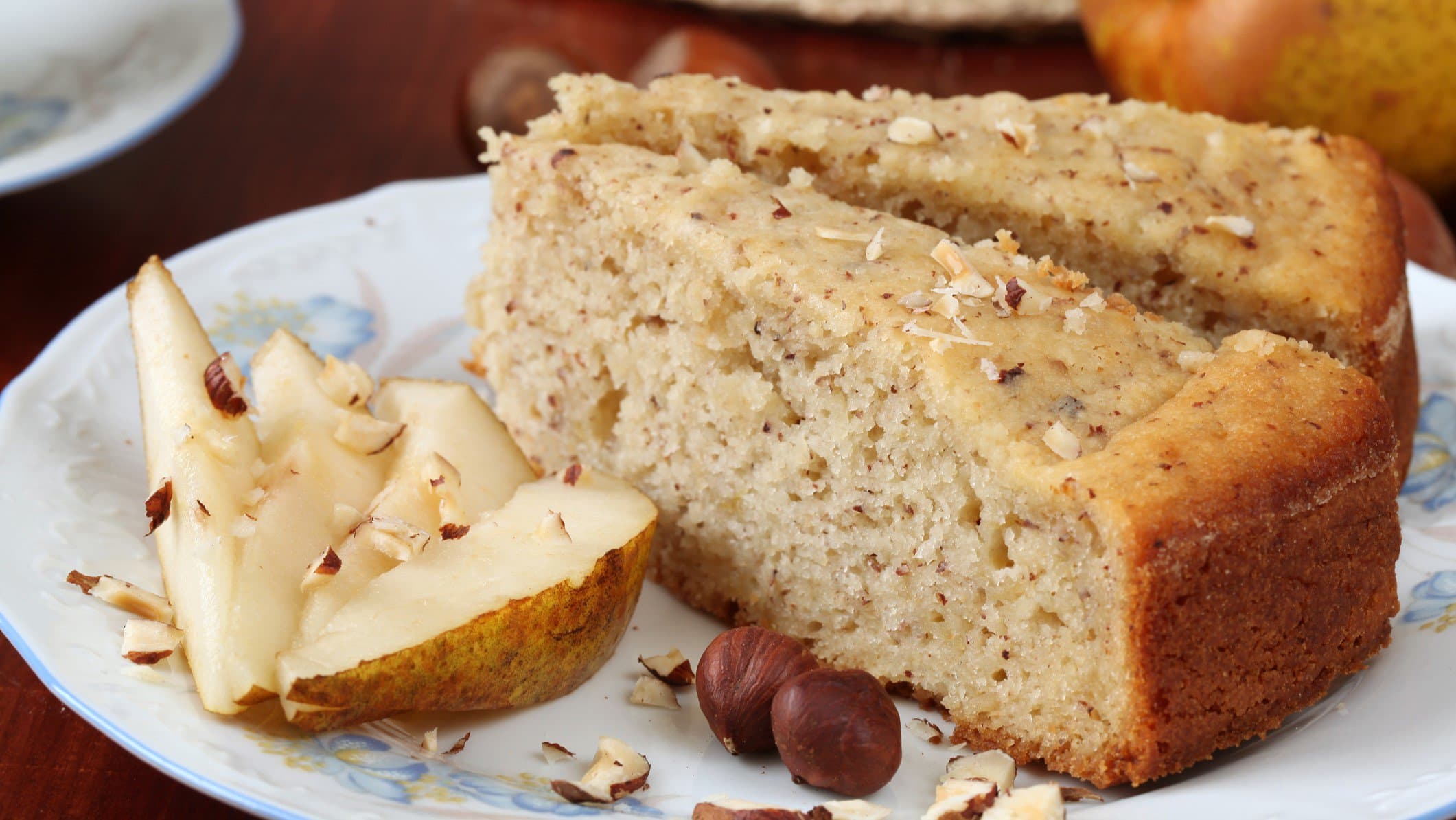 Zwei Stücke Torta Piemontese auf Teller mit Birnenscheiben. Frontalansicht.