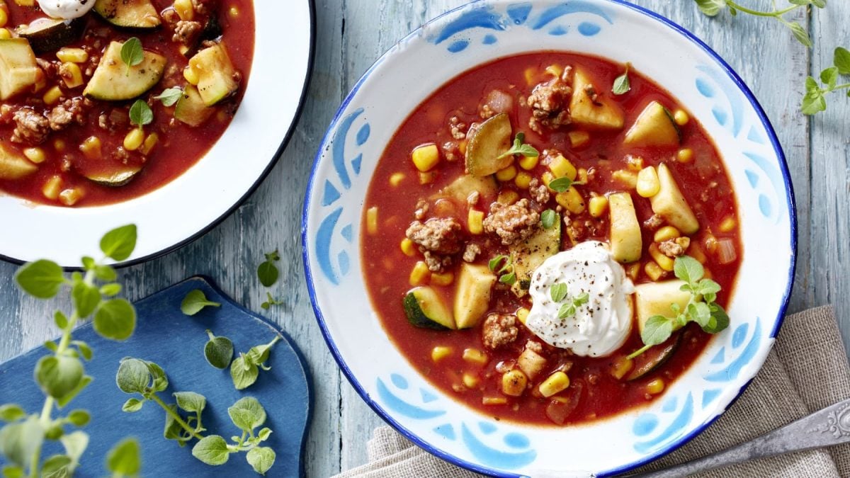 Teller mit Tomaten und Zucchini mit Hackfleisch in der Draufsicht. es handelt sich um einen Eintopf.