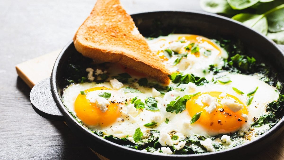 Eine Pfanne auf einem kleinen Schneidebrett mit dem Bärlauch Shakshuka.