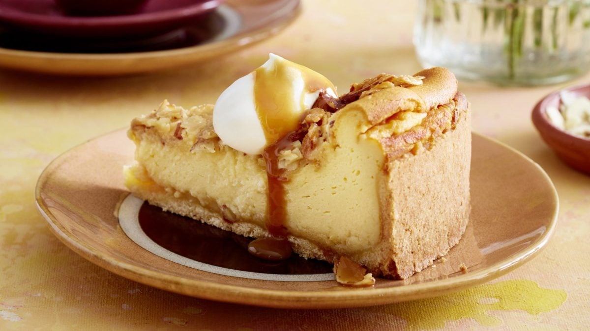 EinTeller mit einem Stück Bienenstich-Käsekuchen auf einem gelben Tisch.