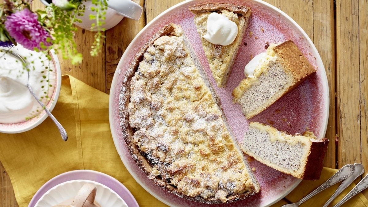 Der Mohn-Käsekuchen mit Streuseln auf einem hellen rosa Teller.