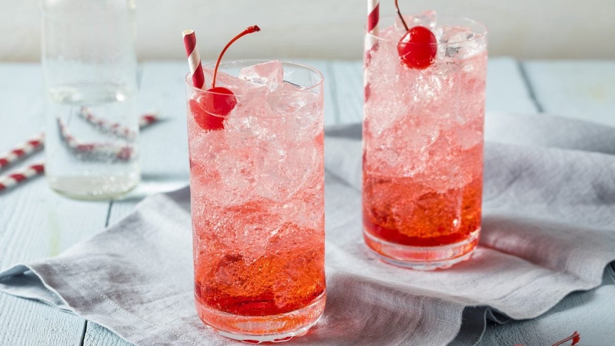 Zwei Gläser Shirley Temple auf einem grauen Küchentuch.