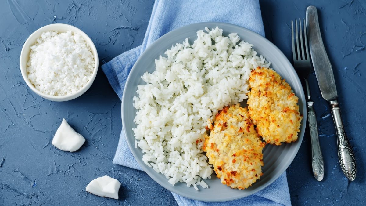 Ein blauer runder Teller mit Hähnchen mit Kokoskruste.