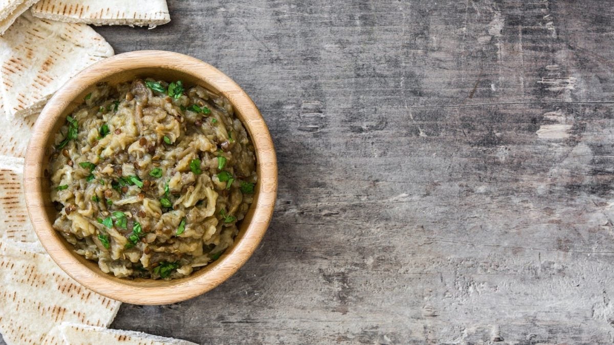 Lib el Kousa, ein Zucchini-Dip, in einer Schale, bestreut mit Minze, Draufsicht, daneben Fladenbrot.