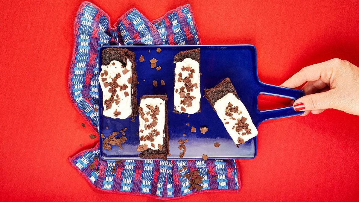 Vier Stücke Mississippi Mud Pie auf einem blauen Tablett, das von einer Hand gehalten wird, alles Draufsicht.