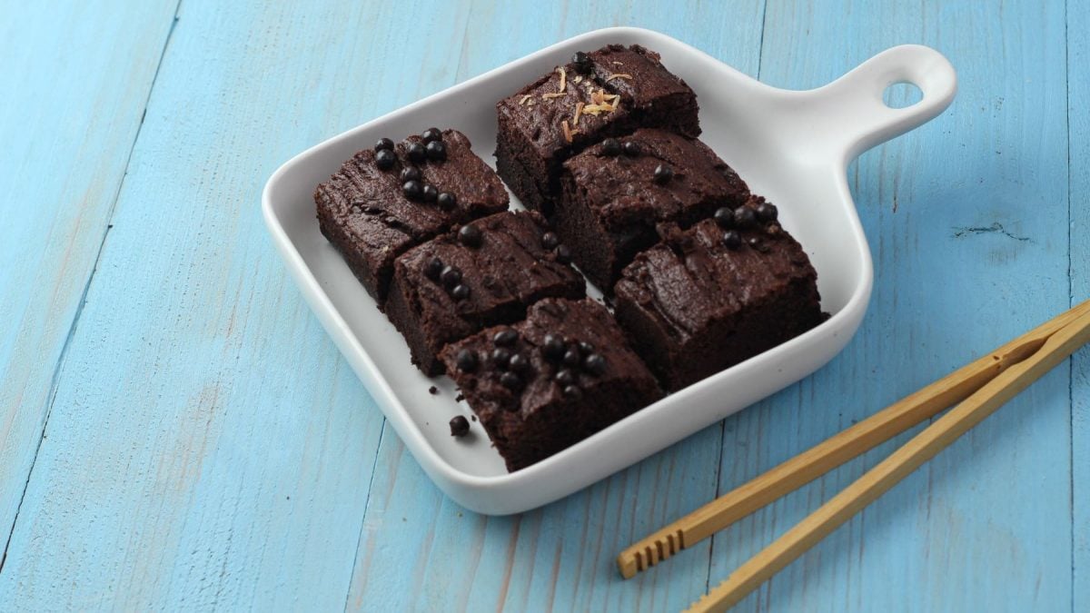 Breakfast Brownie in 2 Minuten aus der Mikrowelle in weißer Form auf blauem Tisch. Daneben Zange aus Holz. Draufsicht..