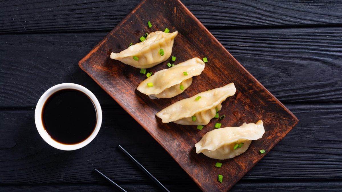 Ein Holztablett mit Jiaozi mit Hack und Lauch.
