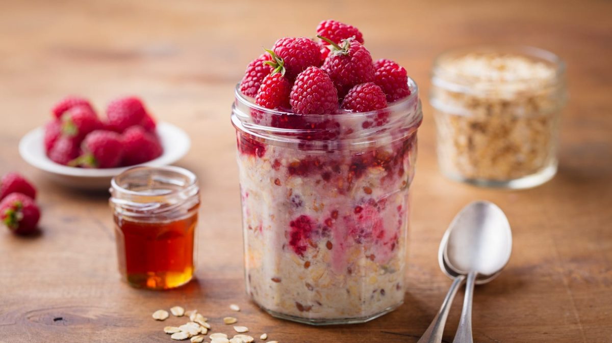 Ein Glas mit Kefir Overnight Oats mit Beeren auf einem Holztisch.