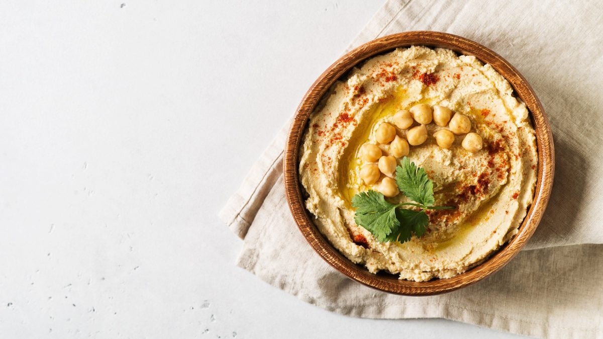Eine Schale Hummus mit Kichererbsen, Gewürzen und Koriander dekoriert.