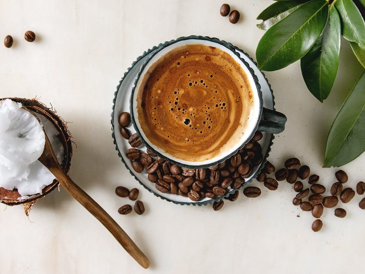 Eine Tasse Coco Coffee neben frischen Kaffeebohnen.