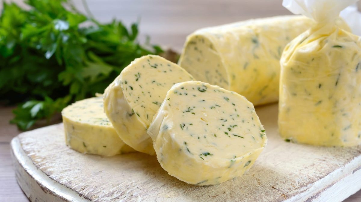 Eine Rolle mit Koriander-Limetten-Butter auf einem Holzbrett.