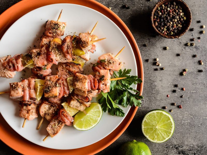 Lachs-Spieße mit Limette auf weißem und braunem Teller.