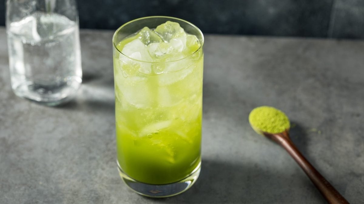 Ein Glas Matcha Soda auf einem grauen Tisch.