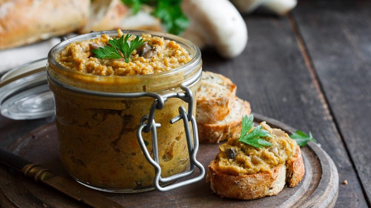 Ein Einmachglas mit Champignon-Linsen-Dip mit Holzbrett.