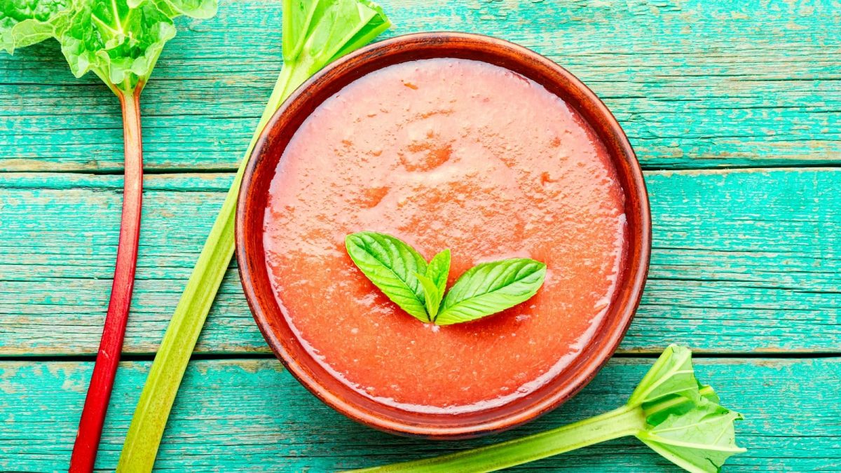 Eine rote Schüssel mit Rhabarber Smoothie Bowl auf eine türkischen Holztisch.