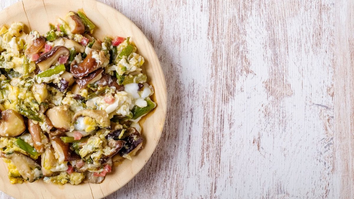 Ein Holztekker mit Spargel-Rührei mit Speck.