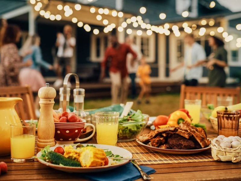 Salate zum Grillen: ein gedeckter Tisch mit gegrilltem Fleisch, Gemüse und Getränken im Garten.