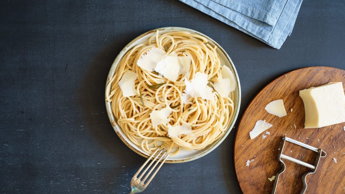 Ein Nudelteller mit Pasta mit Rosmarinbutter auf einem dunkelblauen Hintergrund.