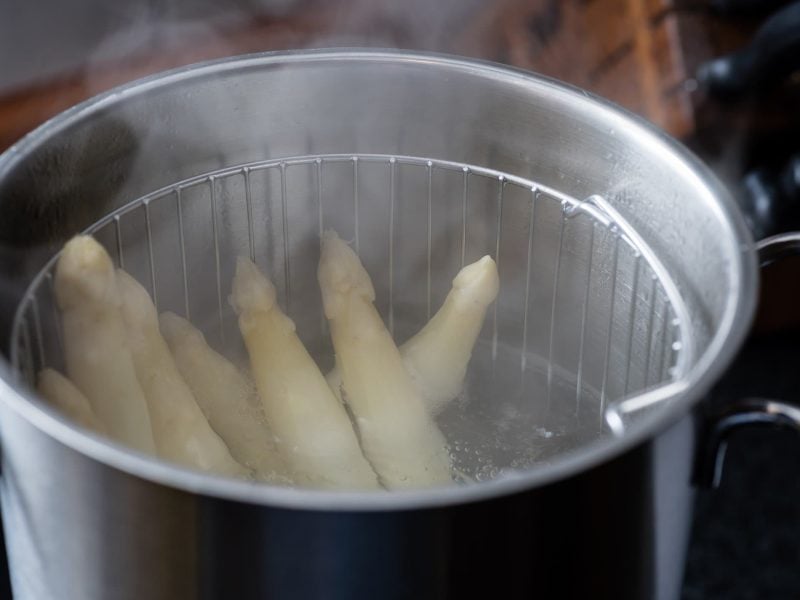 Kann man Spargel aufwärmen restliche Spargelstangen in Spargelkochtopf mit aufsteigendem Dampf. Draufsicht.