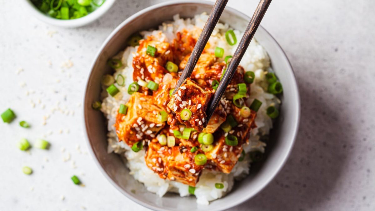 Ein Teller mit Tofu in Gochujang-Sauce auf einem hellen Tisch.