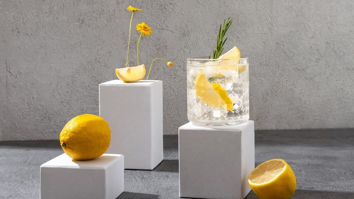 Der Wermut Tonic und frühlingshafte Dekoration auf unterschiedlich hohen weißen Steinblöcken und grauem Tisch.