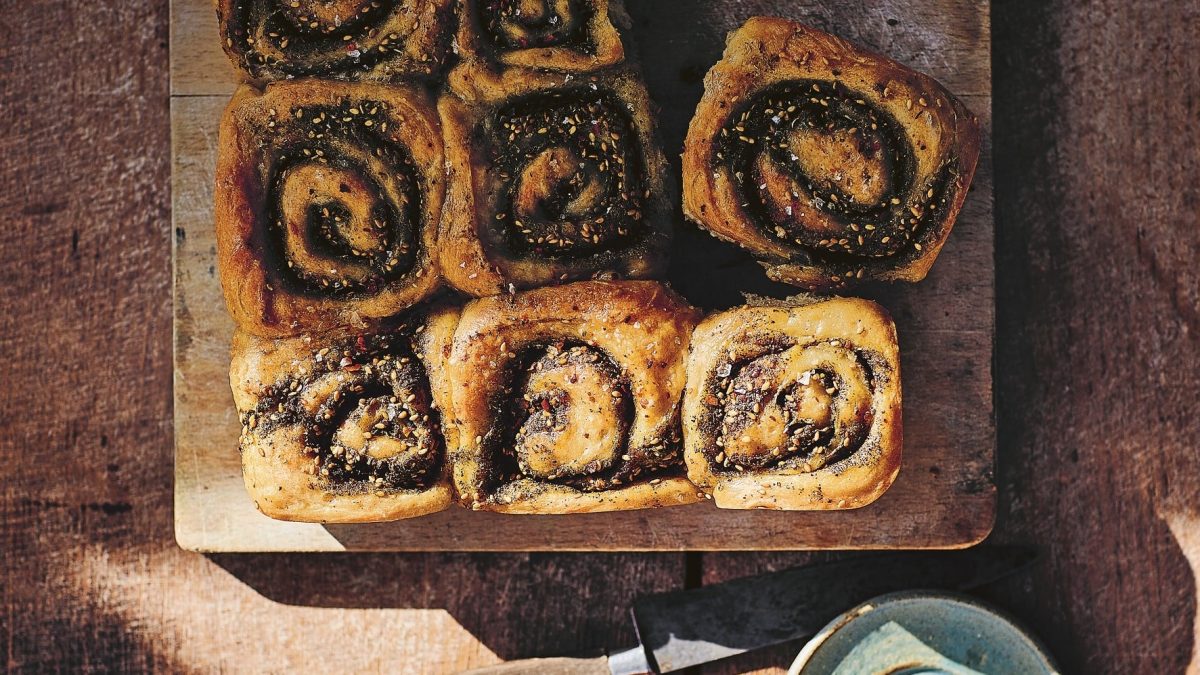Ein Holzbrett mit mehreren herzhaften Za’atar-Schnecken in der Draufsicht.