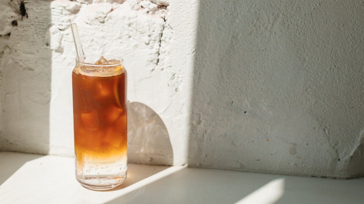 Ein Glas Earl Grey Mule mit Eiswürfeln vor einer sonnigen weißen Wand.