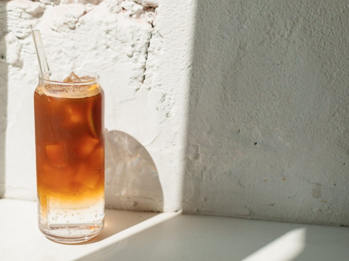 Ein Glas Earl Grey Mule mit Eiswürfeln vor einer sonnigen weißen Wand.