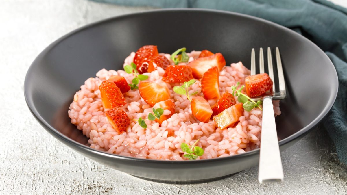 Ein Erdbeer-Risotto in einem dunklen Teller / Gabel / Draufsicht / schräg
