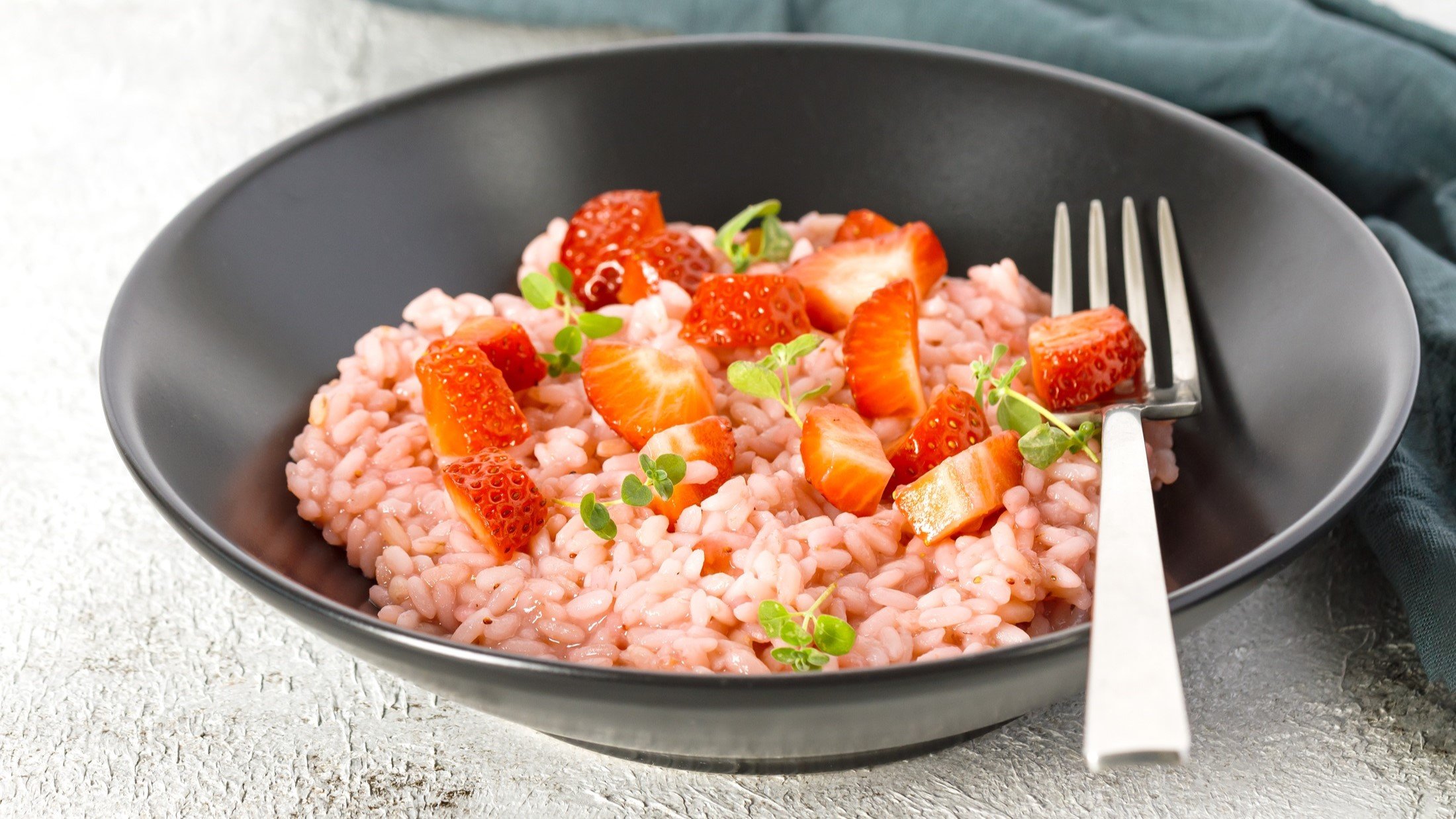 Ein Erdbeer-Risotto in einem dunklen Teller / Gabel / Draufsicht / schräg
